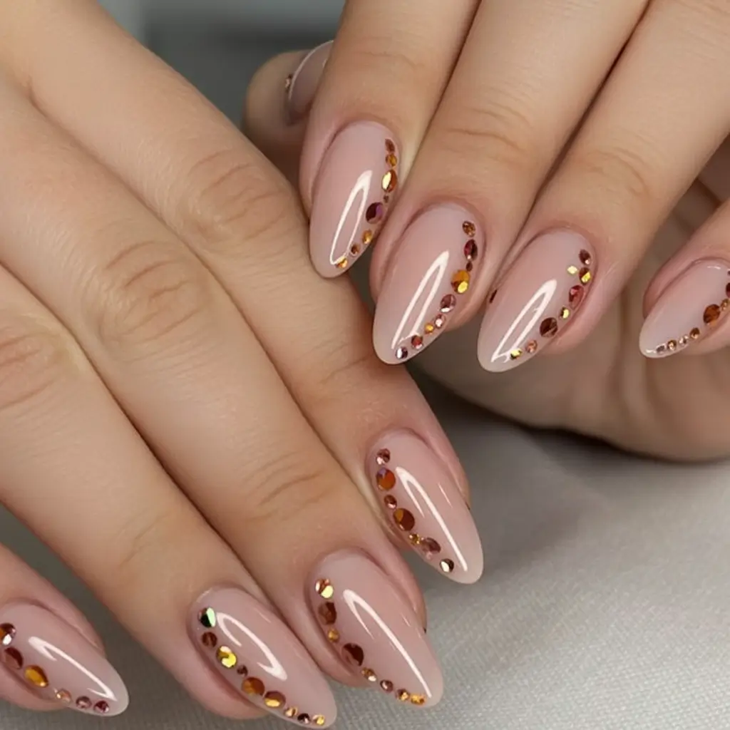Summer 2025 Nail Designs to Try Almond Nude Nails With Amber Rhinestones
